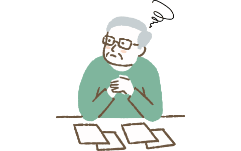 資料を並べて悩む高齢男性